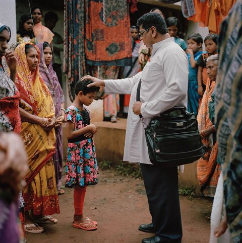 In Odisha India zegent een pastoor een kind en bidt hij voor christelijke vluchtelingen Zestig gezinnen vluchtten naar deze appartementen nadat hun dorp in 2008 werd aangevallen