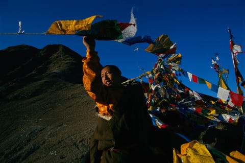 Tijdens Losar de Tibetaanse Nieuwjaarsviering hangt een monnik in Lhasa Tibet gebedsvaantjes op Gedurende het vijftiendaagse feest nemen de gelovigen deel aan een hele reeks rituelen om de loop van het nieuwe jaar te begunstigen