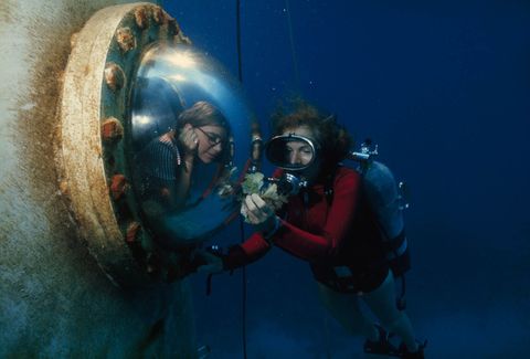 Oceanograaf Sylvia Earle toont ingenieur Peggy Lucas een handvol algen door het raam van de Tektitehabitat Het waren twee van de vijf vrouwen die in 1970 twee weken in de onderwaterhabitat leefden en verschillende aspecten van het zeeleven bestudeerden