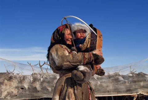 Een Nenetsvrouw in Rusland omhelst haar kleinzoon De familie bereidt zich voor om hun kudde rendieren op de achtergrondte volgen dieperhet Siberische Noordpoolgebied in