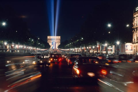 De Arc de Triomphe is een herdenkingsteken voor degenen die vochten in de Franse Revolutie Op deze foto verlicht het verkeer de Champslyses op Bastilledag een nationale feestdag die het begin van diezelfde oorlog herdenkt