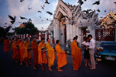 Boeddhistische monniken presenteren aalmoeskommen in Wat Benchamabophit ook bekend als de Marmeren Tempel in Bangkok Thailand De iconische tempel staat afgebeeld op de achterkant van de munt van vijf baht in Thaise valuta