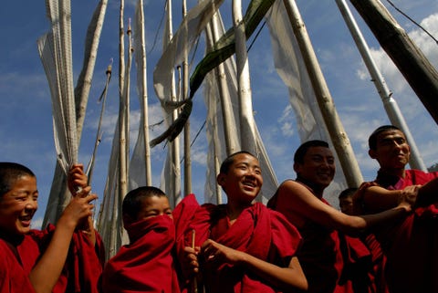 Nieuwe monniken genieten van een pauze onder gebedsvlaggetjesin Kurjey Lhakhang een klooster in Bhutan dat de overblijfselen van de eerste drie koningen van het land herbergt