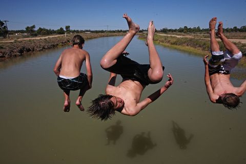 Op een hete zomerdag springen jongens in het Mulwalakanaal bij Deniliquin Australi Het irrigatiekanaal transporteert water meer dan 160 kilometer naar het hart van het boerenland van New South Wales