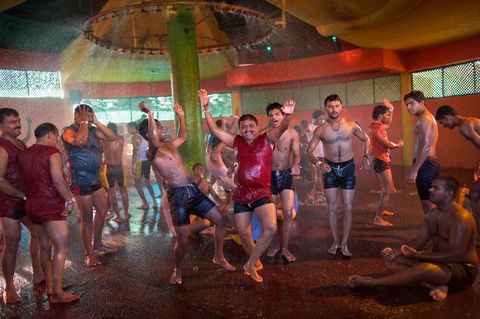 Tijdens het moessonseizoen kan dit themapark opengaan voor nietessentieel watergebruik Deze mannen genieten van het doorweken terwijl ze dansen op een Bollywoodbeat