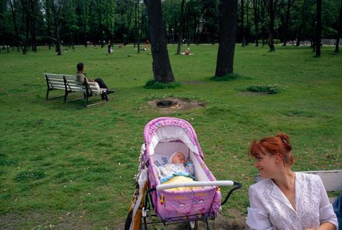 Een moeder bewondert haar slapende baby terwijl ze geniet van een dag in de tuinen van Tauride Palace in St Petersburg Rusland Het paleis werd ooit gebruikt als het zomerhuis van Catharina de Grote
