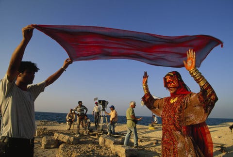 Deze foto uit het nummer van juli 1999 toont de Iraanse filmregisseur Bahram Beyzai in het groen terwijl hij een film aan het opnemen was zeven jaar nadat de nationale censuur zijn vorige project in twijfel had getrokken De actrice in traditionele Baluchikledij is Mozhdeh Shamsai die ook getrouwd is met Beyzai Op de omslag van dit nummer verscheen een closeup van haar