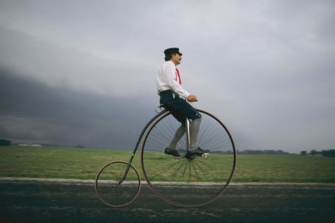 Een man in Indiana VS rijdt op zijn antieke fiets terwijl donkere wolken samenkomen aan de horizon
