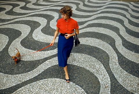 In Rio de Janeiro Brazili loopt een vrouw met haar hond overeenstraatmeteenPortugesestoep een techniek waarbij arbeiders kleine zwarte en witte steentjes bij elkaar leggen om ingewikkelde patronen te creren