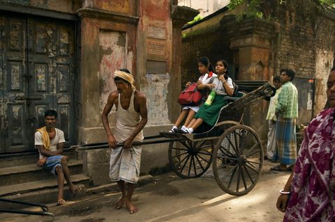 Een riksjatrekker brengt twee kinderen naar school in Kolkata India Toen deze foto werd gepubliceerd in april 2008 was Kolkata aan het overwegen om riksjas volledig te verbieden