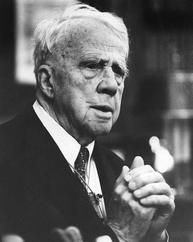 robert frost folding his hands in front of his chest as he looks off camera to the right