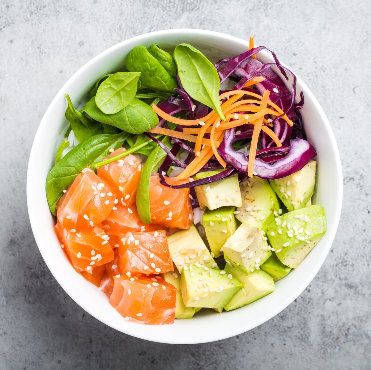 poke bowl with salmon, spinach, avocado, carrot, and red cabbage