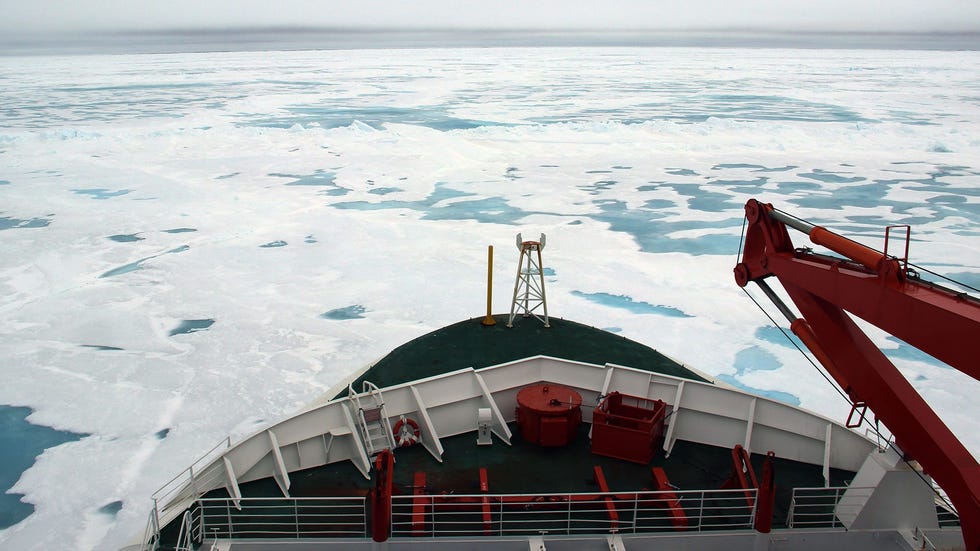 view of ice floes over arctic ocean from the front of a white and red ship