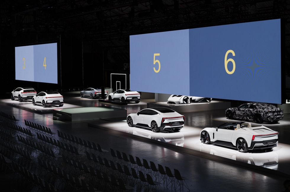 a group of cars parked in front of a large screen