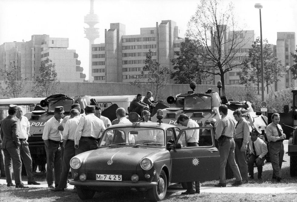 police officers standing around their cars with large skyscrapers in the background