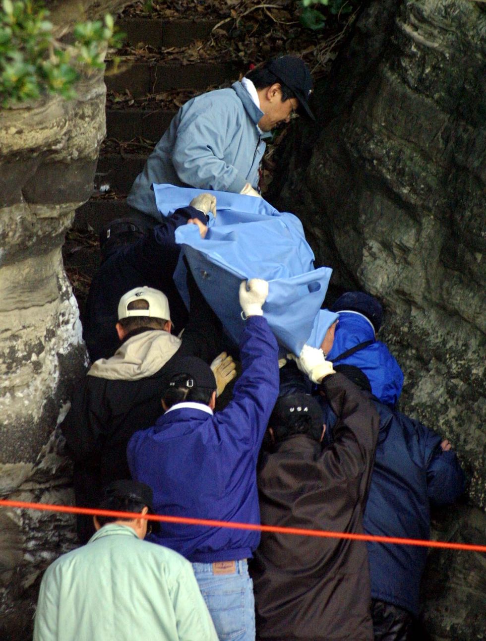 police officers get out of a cave carrying a sheet