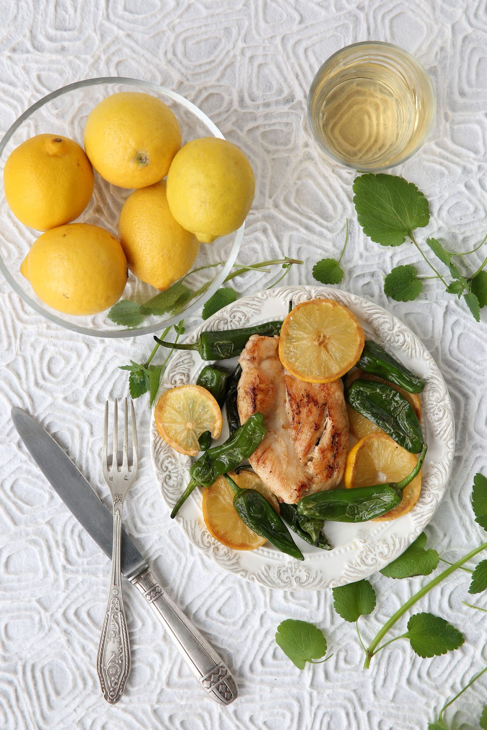 una fuente con limones junto a un plato con pollo, limones y pimientos