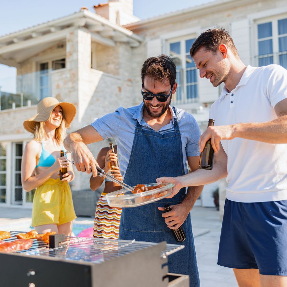 two people taking over the grill barbecueing during a pool party at a beach house