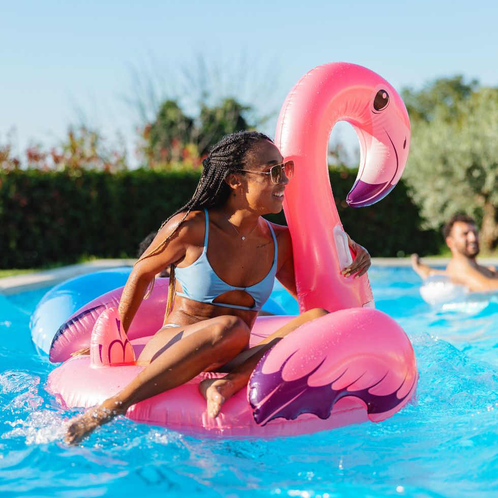 woman enjoys a hot summer day in the pool with a giant inflatable flamingo float