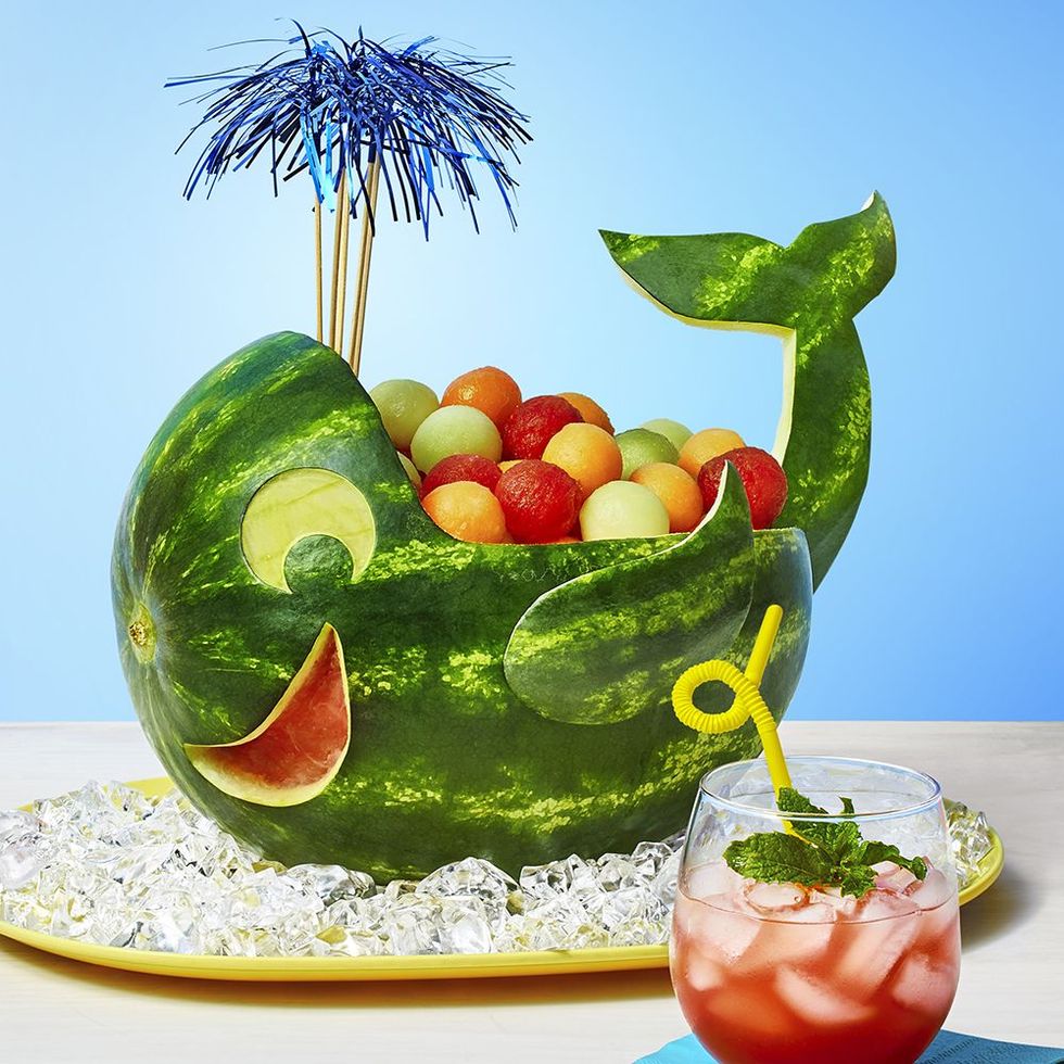 watermelon carved into a whale holding fruit salad
