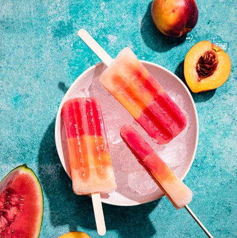 homemade ice cream popsicles in a bowl with ice, made with watermelon and peach, under hard light