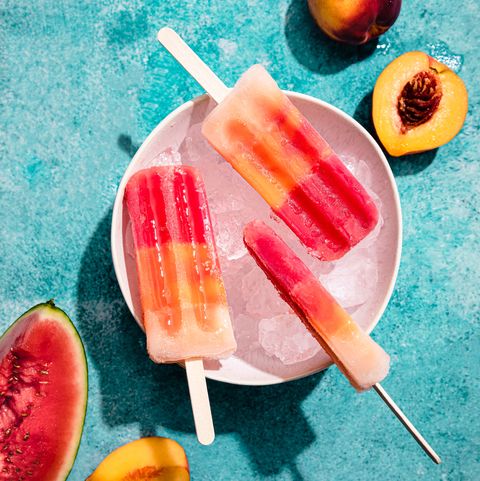 homemade ice cream popsicles in a bowl with ice, made with watermelon and peach, under hard light
