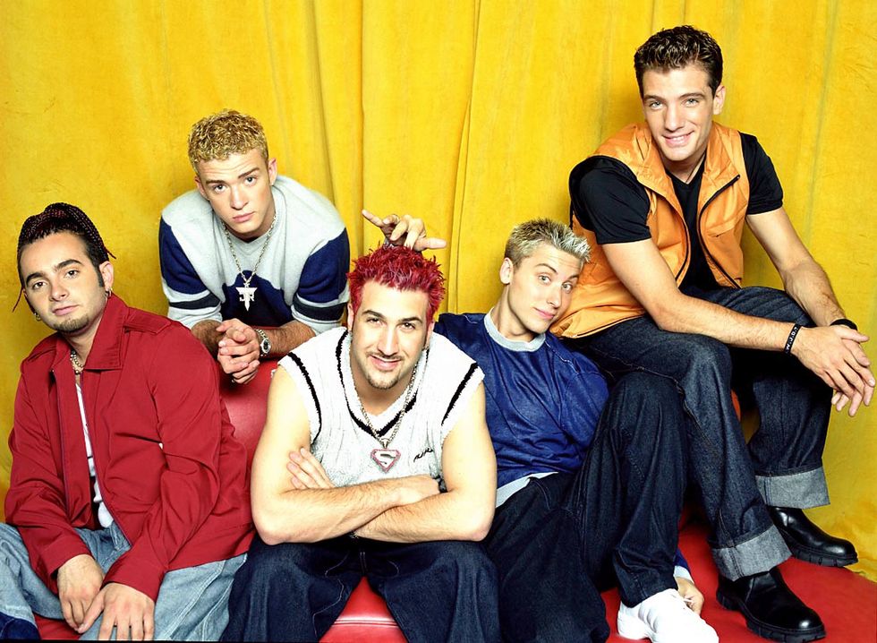 chris kirkpatrick, justin ﻿timberlake, joey fatone, lance bass, and jc chasez pose for a photo while sitting in front of a yellow background