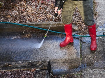 person using a pressure washer on a surface outdoors