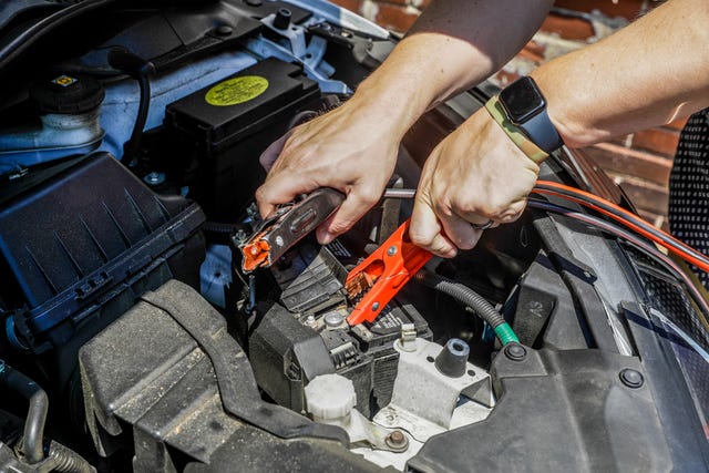 a person attaching jumper cables to a car