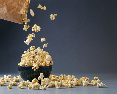 Popcorn flying into the bowl over grey background