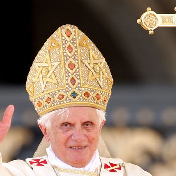 pope benedict xvi smiles and waves, he wears white robes and a golden pontiff hat
