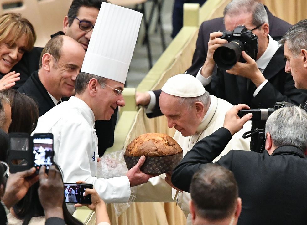 pope francis smells a panettone offered to him by a pastry chef