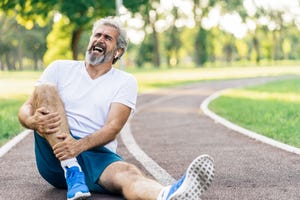 un hombre que estaba corriendo se duele de dolor de piernas sentado en el suelo