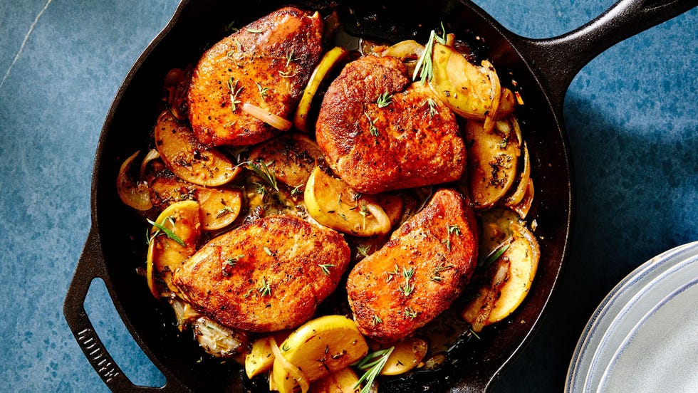 pork chops with apples in a skillet with fresh herbs