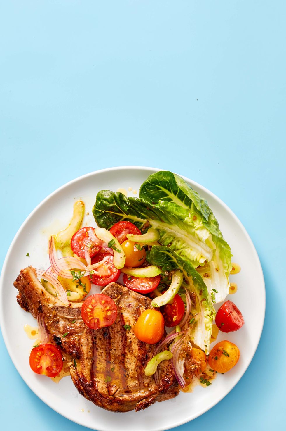 https://hips.hearstapps.com/hmg-prod/images/pork-chops-with-bloody-mary-tomato-salad-1619657081.jpg?crop=0.692xw:0.763xh;0.121xw,0.127xh&resize=980:*