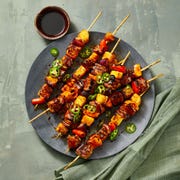 pork, pineapple and onion skewers on a black plate