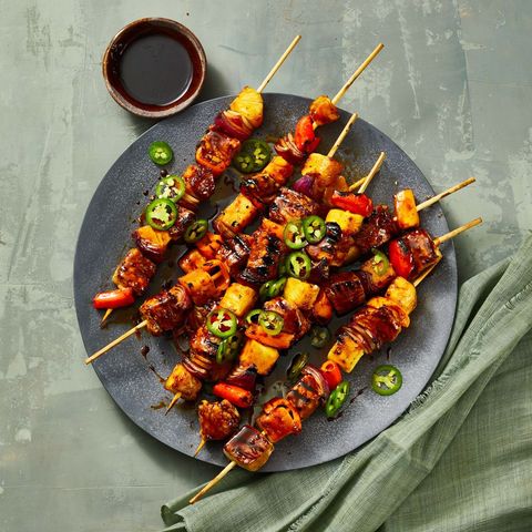 pork, pineapple and onion skewers on a black plate