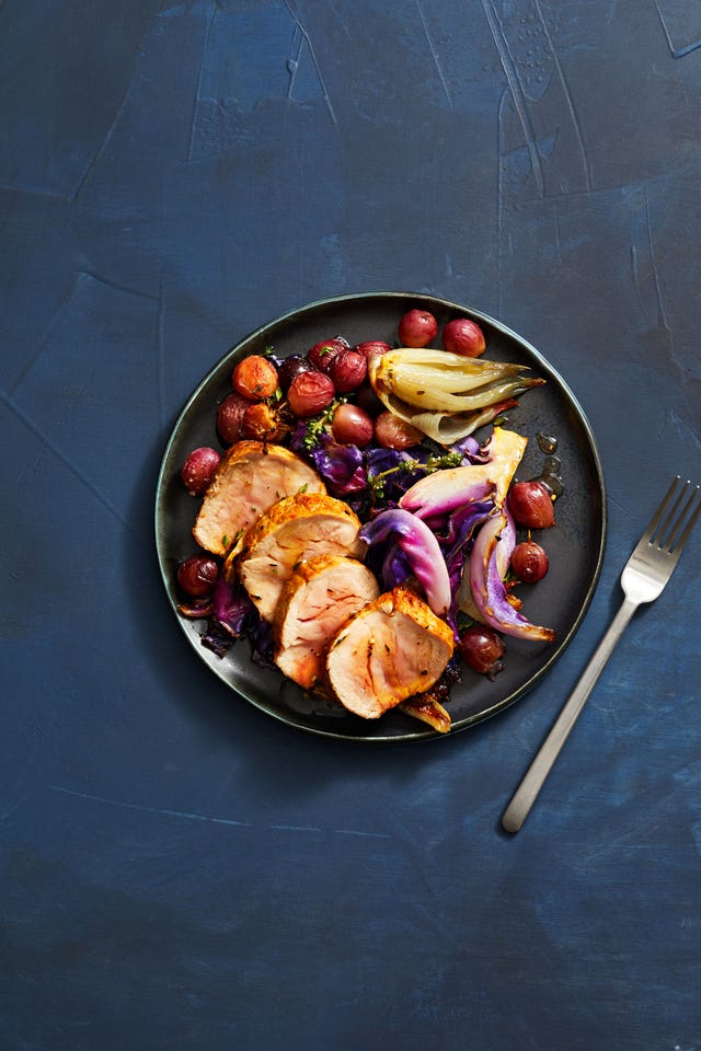pork tenderloin with roasted red grapes and cabbage on a black ceramic plate