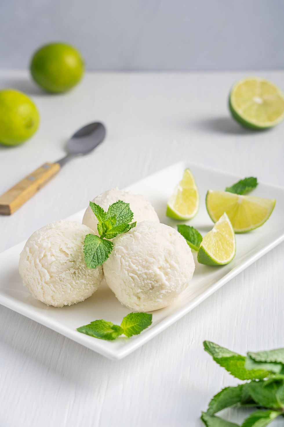 portion of fresh sweet scoop of lime and mint ice cream served on plate on white wooden background