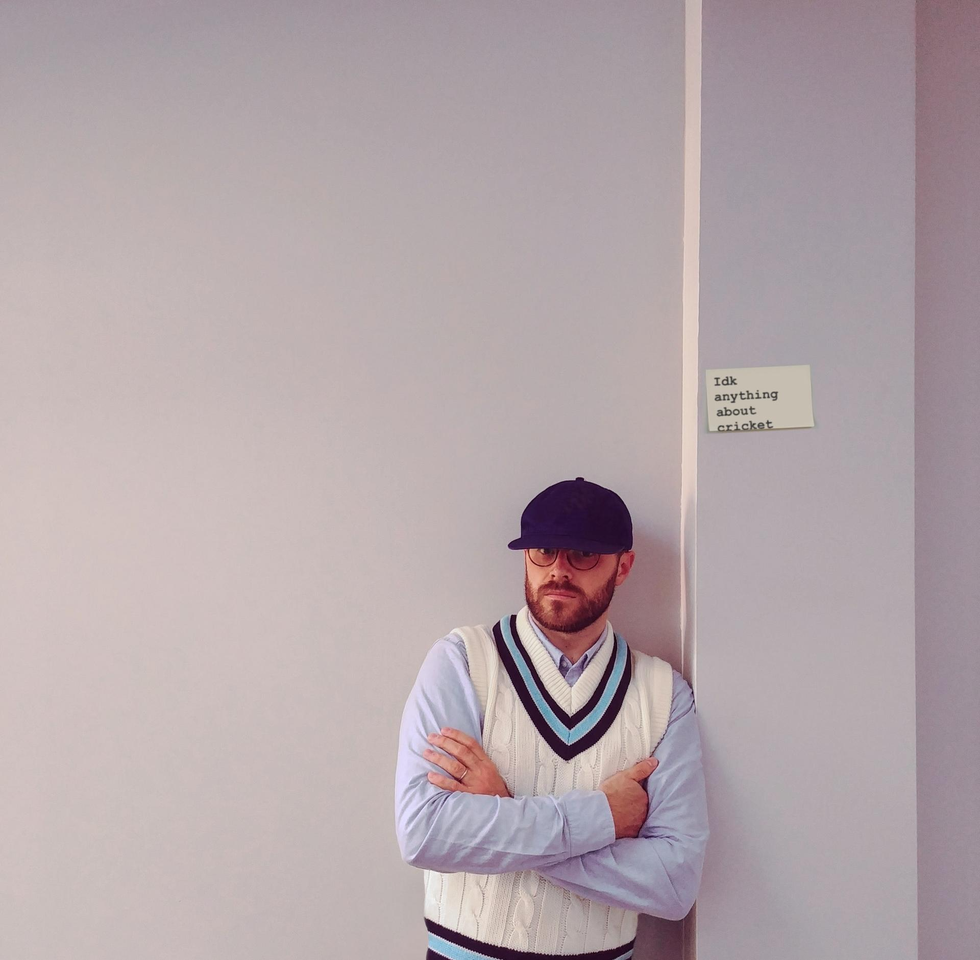 a person in a white shirt and blue hat with the arms crossed