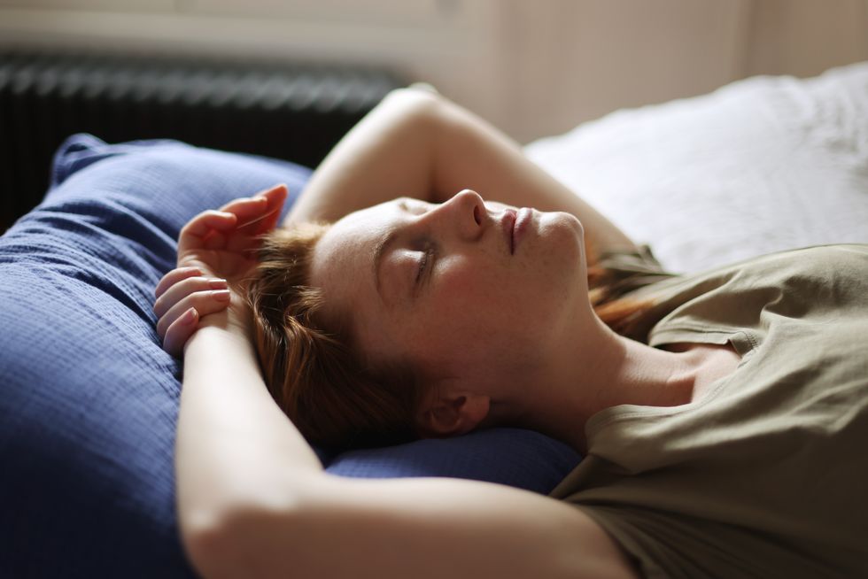 portrait of a beautiful redhead woman laying on her bed at home