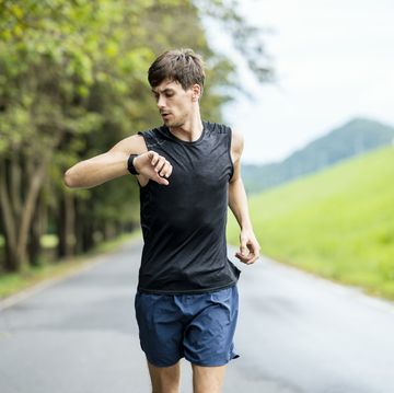portrait of a caucasian male athlete using wearable run tracking technology while jogging on the street healthy, active lifestyle concept