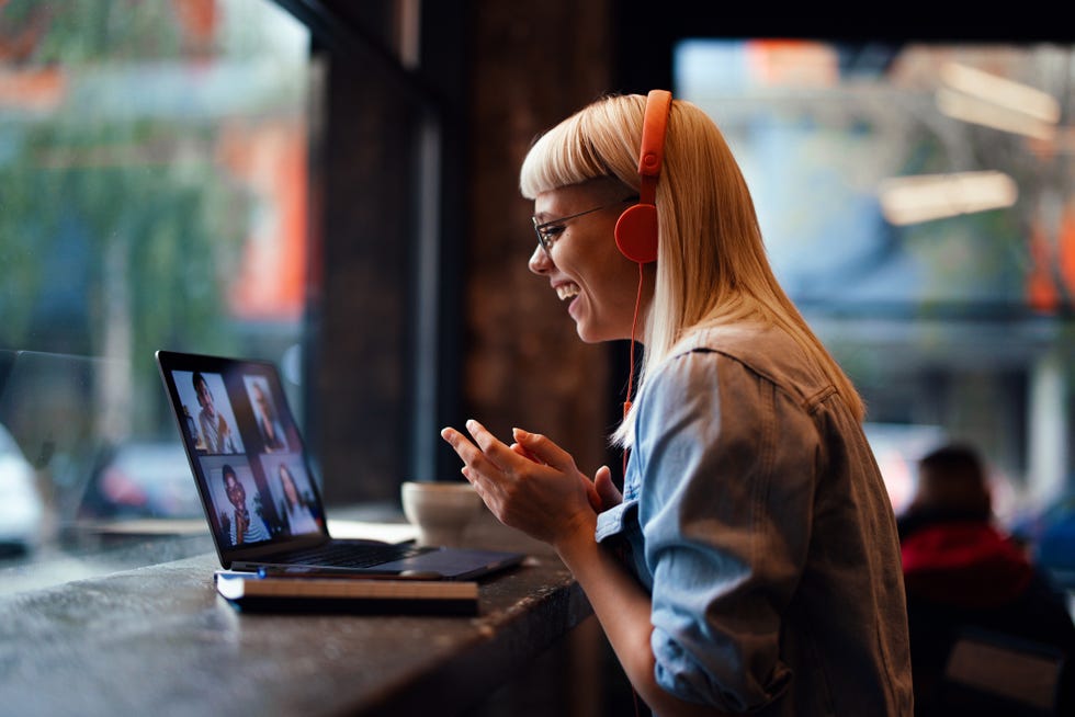 portrait of a cheerful beautiful young woman having an online meeting on her laptop in the cafeteria copy space