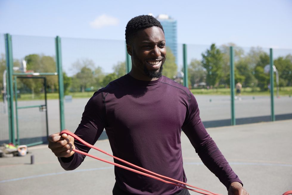 a portrait of a fitness coach at a training session in a local park smiling off camera