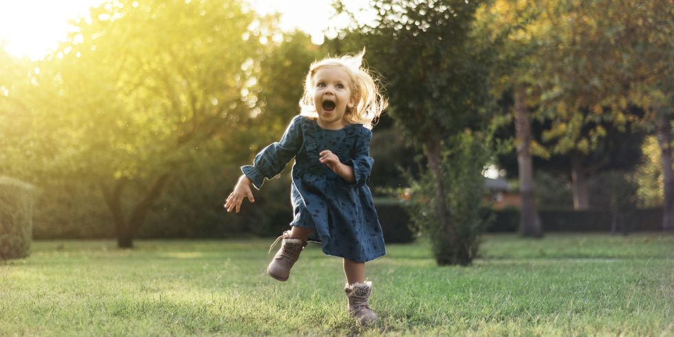 niña feliz con botas corriendo por el campo