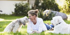 portrait of a mature content woman getting kisses from her dog in her garden
