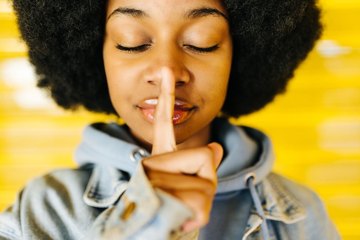 portrait of a pretty young afro girl showing silence gesture