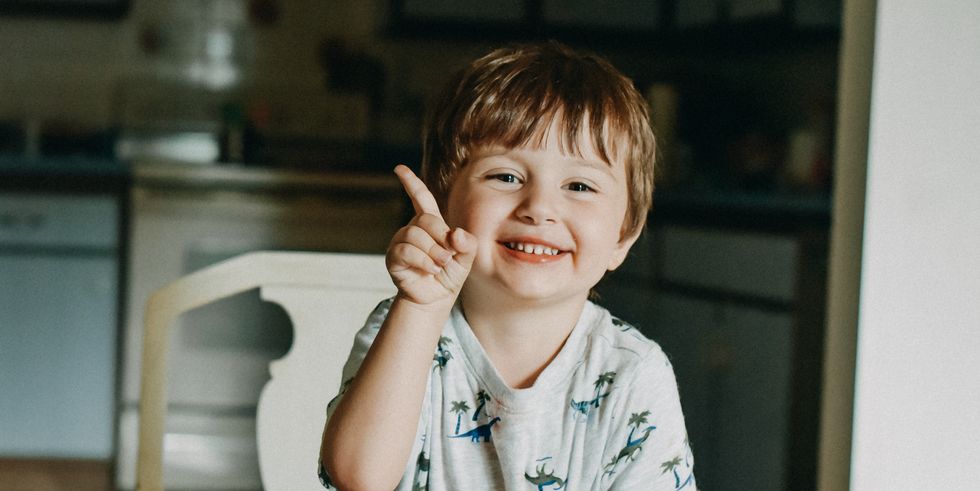 portrait of a smiling toddler while raising his index finger