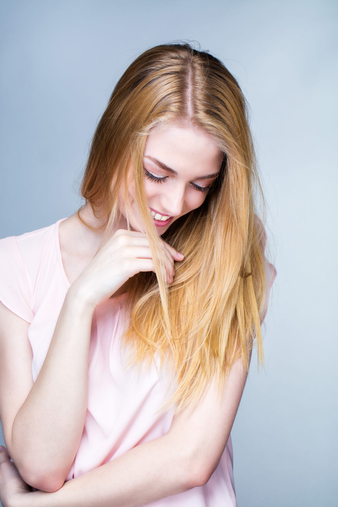Portrait of a smiling young woman, her head down, one hand under the chin