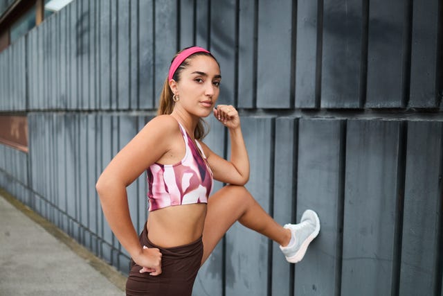 portrait of a young fit sportswoman looking at the camera while stretching her legs during a cardio workout